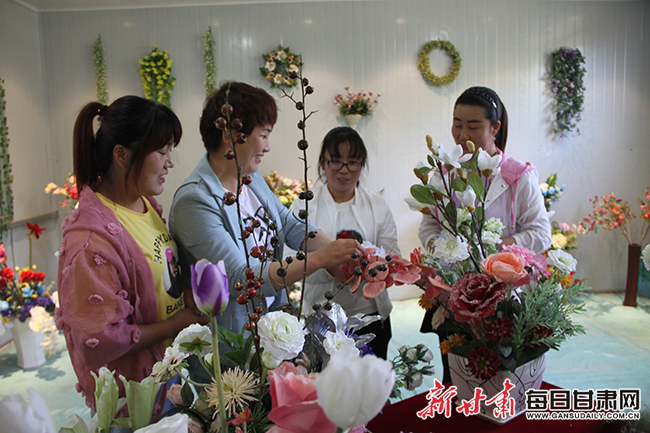 岳彩霞指导车间员工制作仿真花.jpg